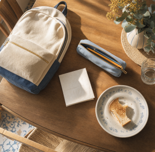 Mesa de desayuno con mochila y estuche escolar vista desde arriba - blog de Clínica Lazos